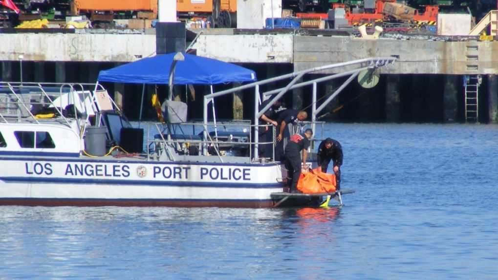 Členovia pobrežnej polície vyťahujú telo Tony Scotta z vody neďaleko mosta The Vincent Thomas Bridge.