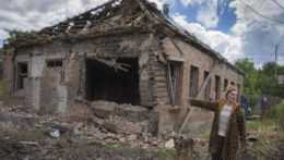 žena ukazuje na zničený dom v Bachmute