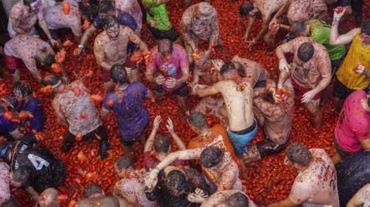 Ľudia sa ohadzujú paradajkami.