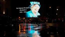 Obraz kráľovnej Alžbety II. na veľkej obrazovke v daždivej ulici na Piccadilly Circus v Londýne.