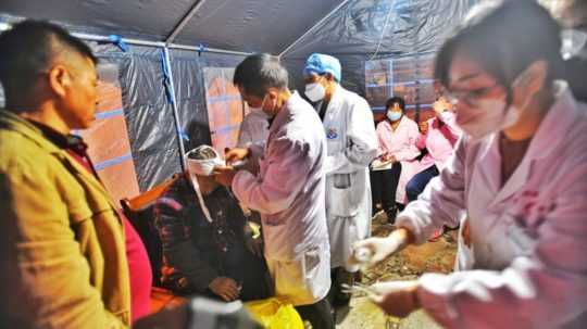 Záchranári ošetrujú preživších v núdzovom prístrešku v obci Mo-si po zemetrasení s magnitúdou 6,8.