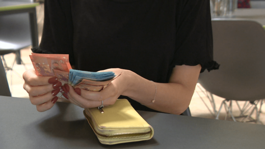 Žena na snímke vyťahuje z peňaženky eurobankovky.