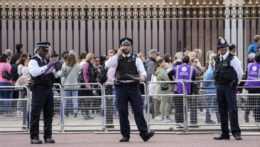Policajti hliadkujú pred Buckinghamským palácom a za nimi stoja ľudia v dlhom rade, aby si uctili pamiatku zosnulej britskej kráľovnej Alžbety II.