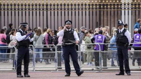 Policajti hliadkujú pred Buckinghamským palácom a za nimi stoja ľudia v dlhom rade, aby si uctili pamiatku zosnulej britskej kráľovnej Alžbety II.