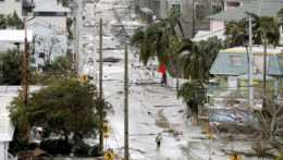 Muž kráča cez ulicu posiatu troskami zo zničených domov a obchodov v meste Fort Myers na Floride.
