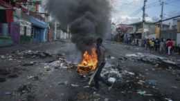 Muž kráča okolo horiacich pneumatík počas protivládnych protestov v haitskej metropole Port-au-Prince