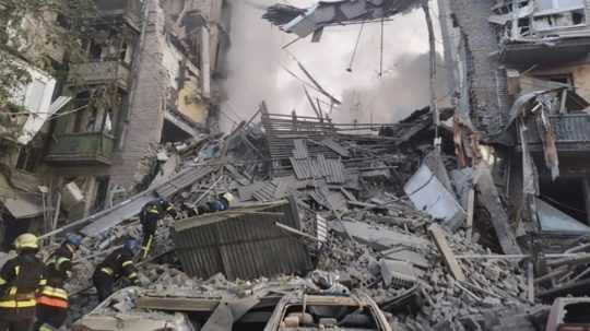 Záchranári prehľadávajú trosky budovy po útoku na mesto Záporožie na juhovýchode Ukrajiny.