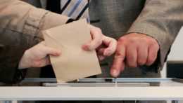 Na snímke osoba hádže obálku do hlasovacej urny.