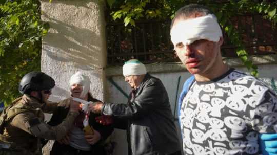 Vojaci ošetrujú ľudí v Kyjeve, ktorí utrpeli zranenia po ruskom útoku.