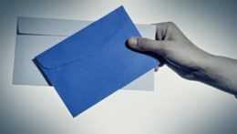 Ruka drží bielu a modrú obálku