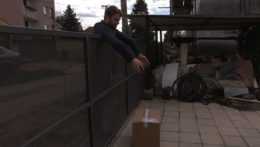 Na snímke zákazník demonštruje prehodenie balíka s kávovarom cez plot.