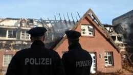 Na snímke stojí dvojica nemeckých policajtov pred budovou zhorenej ubytovne.