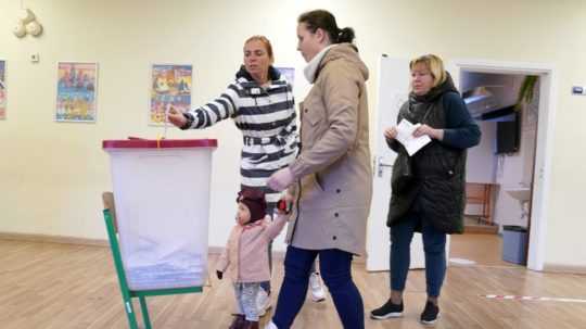 Ľudia hlasujú vo volebnej miestnosti počas parlamentných volieb v Lotyšsku 1. októbra 2022 v Rige.