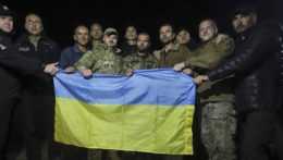 Na snímke ukrajinskí vojaci držia ukrajinskú vlajku.