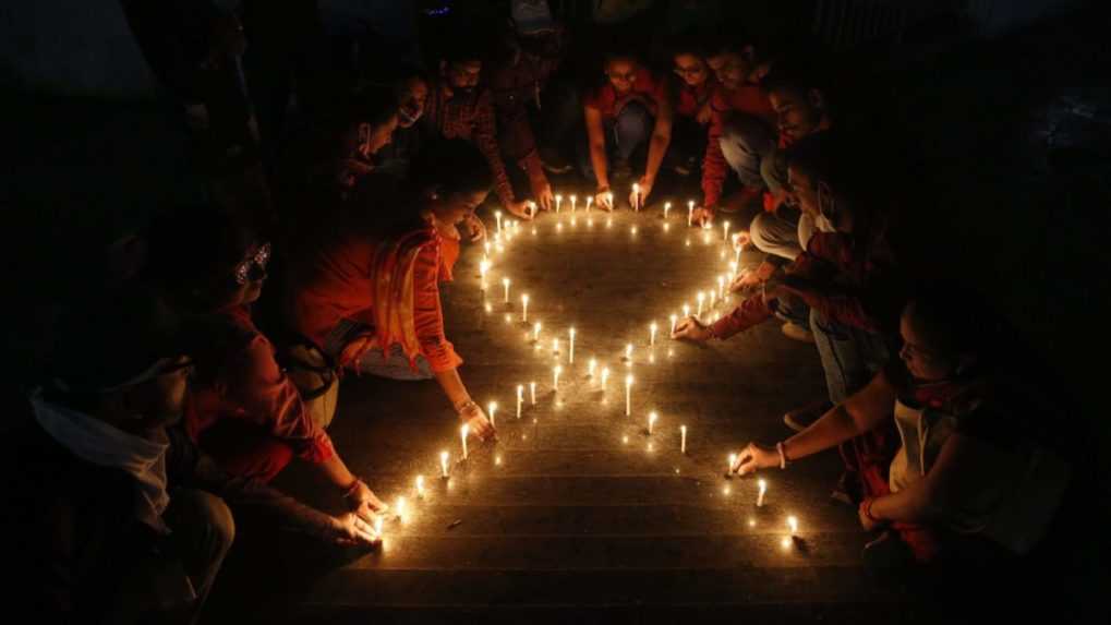 Členovia mimovládnej organizácie vytvárajú zo zapálených sviečok červenú stuhu v indickom meste Ahmedabád.