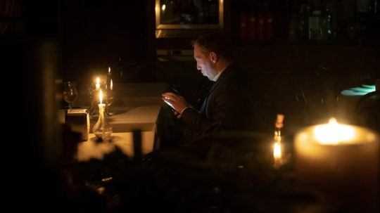 Muž sedí v kaviarni pri sviečkach počas výpadku elektriny v Kyjeve.