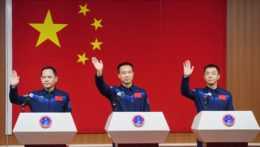 Na snímke sú traja muži pred Čínskou vlajkou.