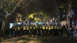 Čínski policajti blokujú prístup do jednej z ulíc Šanghaju, kde sa zišli protestujúci.