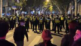 Čínski policajti blokujú miesto, kde sa zhromažďujú demonštranti počas protestu proti covidovým opatreniam v Šanghaji.