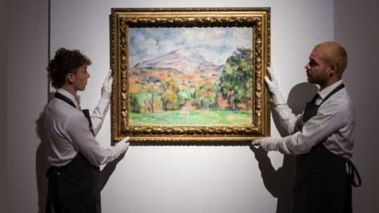 Na snímke dvaja muži v bielych rukavičkách držia obraz krajinky