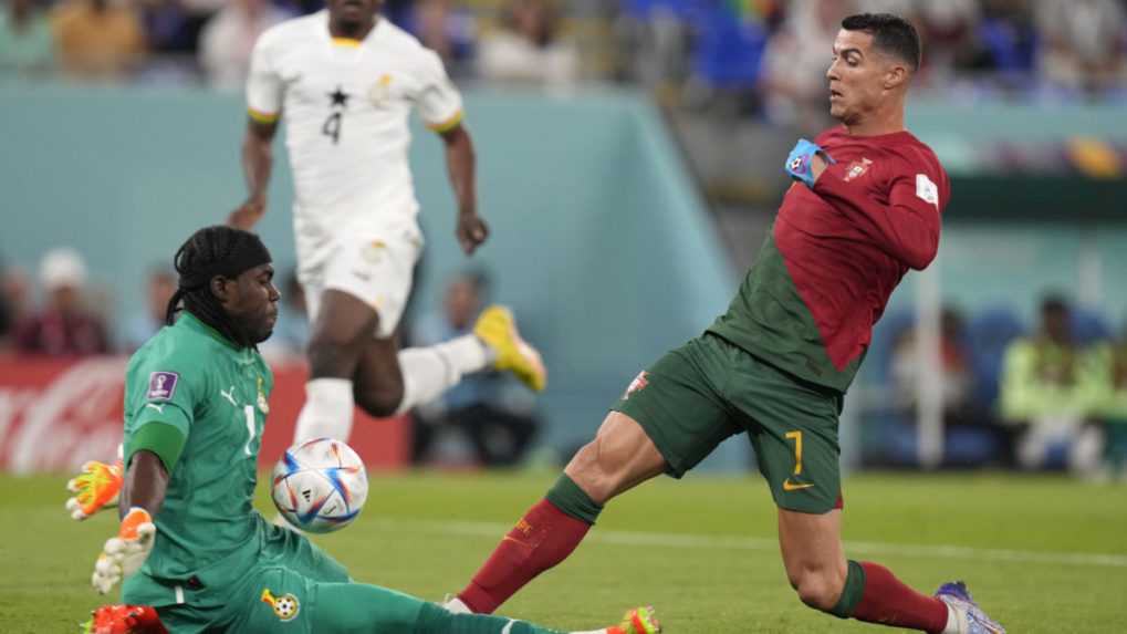 Ghanský brankár Lawrence Ati-Zigi (vľavo) chytá pred Portugalcom Cristianom Ronaldom vo futbalovom zápase.
