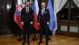 Premiéri Eduard Heger a Petr Fiala stoja pred vlajkami Česka, Slovenska a Európskej únie pred začatím spoločnej pracovnej večere
