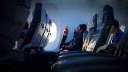 Na snímke muž používajúci mobilný telefón na palube lietadla.