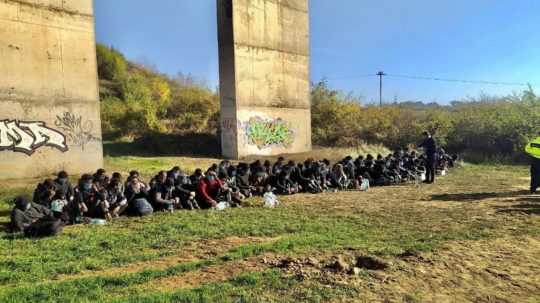 Na snímke zadržaní migranti zhromaždení pod diaľničným mostom.