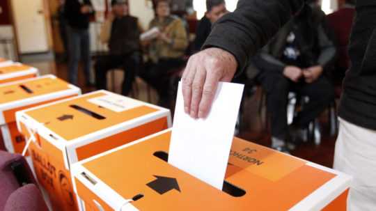 volič vhadzuje volebný lístok do urny