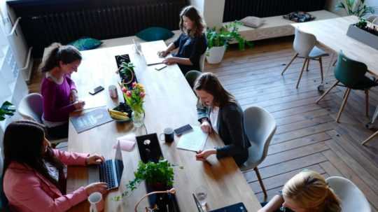 Na snímke skupina žien sedí za stolom a pracujú na počítačoch.