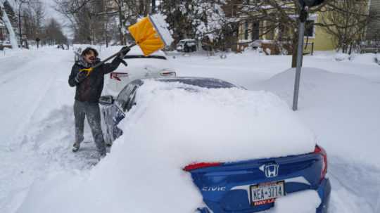 Muž odhrabáva sneh zo svojho auta po extrémnej snehovej búrke v americkom meste Buffalo.