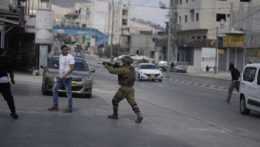 Na archívnej snímke izraelský vojak mieri zbraňou na Palestínčanov.