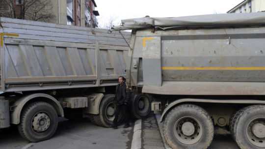 Muž prechádza okolo barikády z nákladných áut na ulici v severnej časti etnicky rozdeleného mesta Mitrovica v Kosove.