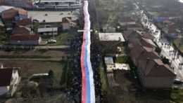 Kosovskí Srbi nesú obrovskú srbskú zástavu počas protestu.