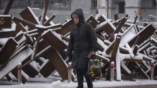 Na ilustračnej snímke žena kráča centrom Kyjeva. V pozadí vidno takzvaných protiraketových ježkov