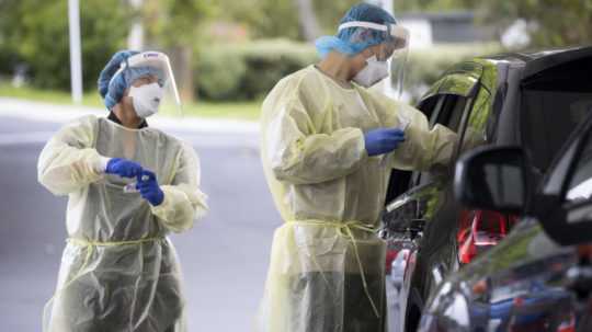 Zdravotníci testujú ľudí z auta na ochorenie COVID-19 v Aucklande na Novom Zélande.