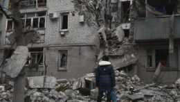 Na snímke sa žena pozerá na bytovku zničenú po nedávnom ruskom raketovom útoku v meste Časiv Jar.