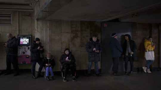 Ľudia sa pozerajú do svojich mobilov v metre pri leteckom bombovom poplachu v Kyjeve.