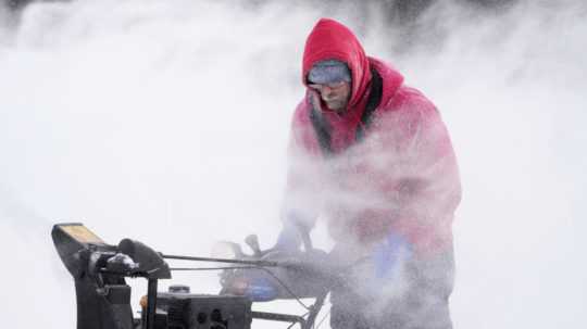 Muž odstraňuje sneh z klziska v centre meste Des Moines, americkom štáte Iowa.