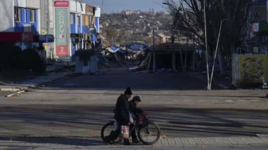 Miestni obyvatelia jazdia na bicykli po ulici v oblasti ťažkých bojov s ruskými silami v meste Bachmut.