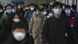 Cestujúci ochranných rúškach na stanici metra v Pekingu.
