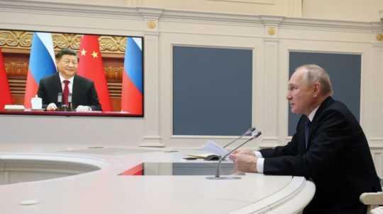 Ruský prezident Vladimir Putin (vpravo), ktorý rokuje s čínskym prezidentom Si Ťin-pchingom (na obrazovke vľavo) prostredníctvom videospojenia v Moskve.