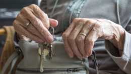 Na snímke je seniorka, ktorá vkladá do kabelky kľúče.