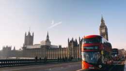 Na ilustračnej snímke typický červený poschodový autobus a budova londýnskeho parlamentu v pozadí.