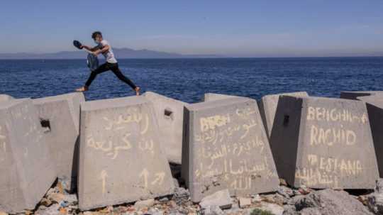 Migrant skáče po ochrannej hrádzi v španielskej enkláve Ceuta v severnej Afrike.