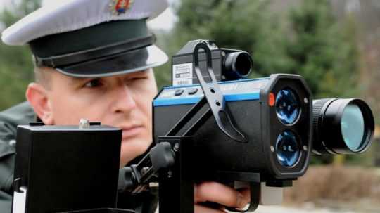 Na snímke policajt pri meraní rýchlosti laserovým radarom.