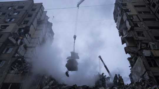Záchranári prehľadávajú trosky výškovej obytnej budovy po sobotňajšom raketovom útoku ruskej armády v meste Dnipro.