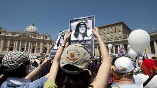 Na archívnej snímke ľudia držia fotografie zmiznutého dievčaťa Emanuely Orlandiovej na Námestí sv. Petra vo Vatikáne.