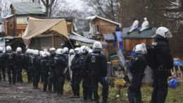 Policajti stoja v tábore klimatických aktivistov v dedine Lützerath.