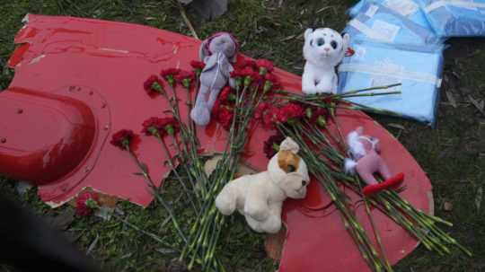 Kvety a plyšové hračky na časti vrtuľníka, ktorý sa zrútil pri budove materskej školy a bytovky v meste Brovary.
